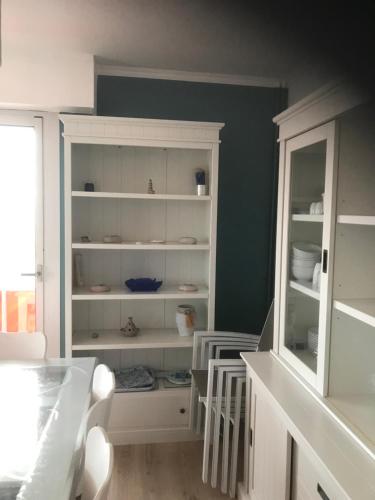 a kitchen with white shelves in a room at LES BALCONS ROUGES - FACE MER in Sainte-Cécile-Plage