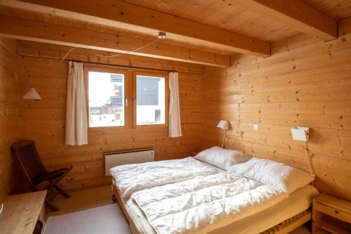 Una cama en una habitación de madera con ventana. en Artus 6, en Bettmeralp
