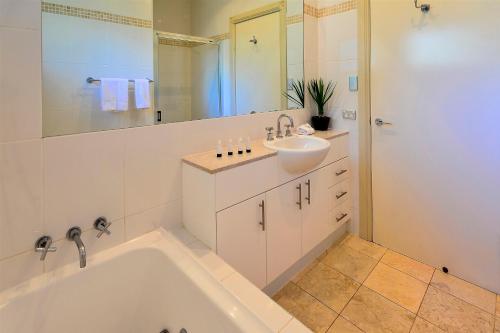 y baño con bañera, lavabo y espejo. en Blue Water Views Apartments, en Hamilton Island