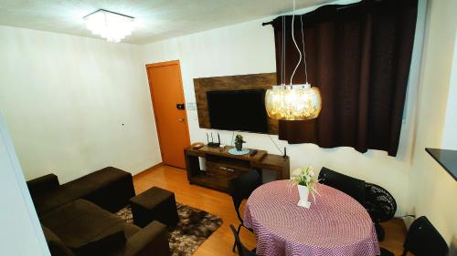 a living room with a table and a television at Apto Executivo Ravena in Campo Grande