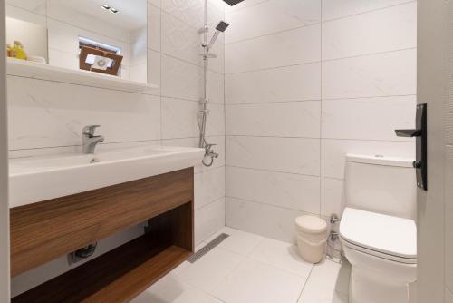a white bathroom with a sink and a toilet at Assos Kartal Yuvasi Hotel in Sazlı