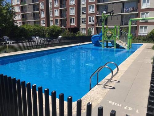 uma grande piscina azul com parque infantil em Departamento 3 Personas em Chillán