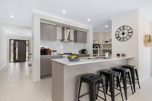 a kitchen with a counter and some stools in it at Winter Valley Retreat - Palatial Pad in the Valley! in Alfredton