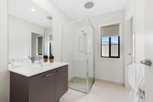 a white bathroom with a sink and a shower at Winter Valley Retreat - Palatial Pad in the Valley! in Alfredton