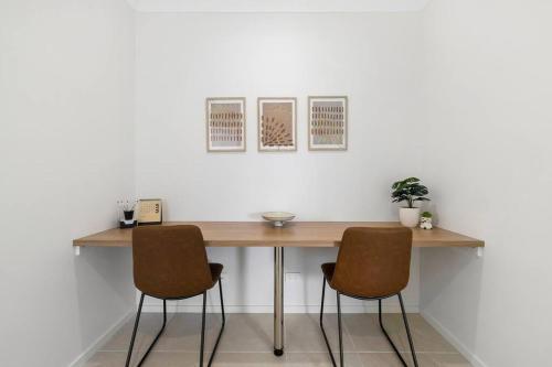 a wooden table with two chairs in front of a wall at Winter Valley Retreat - Palatial Pad in the Valley! in Alfredton
