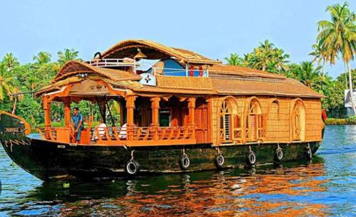 un barco de madera en el agua con una casa en él en Marari La Rose Beach Homestay, en Mararikulam