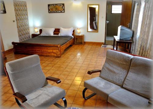 a bedroom with a bed and two chairs at Hotel Aurore Lomé in Lomé