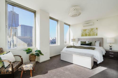 1 dormitorio con cama blanca y ventanas grandes en Urban Oasis on Collins en Melbourne