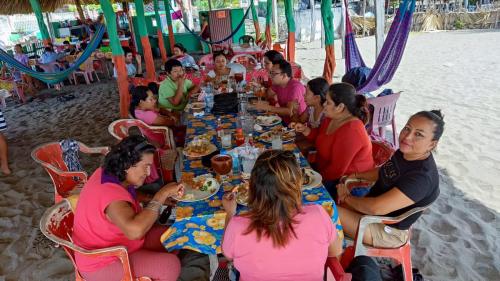 a group of people sitting at a table on the beach at Barra Zacapulco - Palapa Abraham 