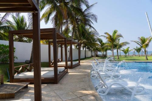 a pool with white chairs next to a resort at Villas La Mar in Monterrico