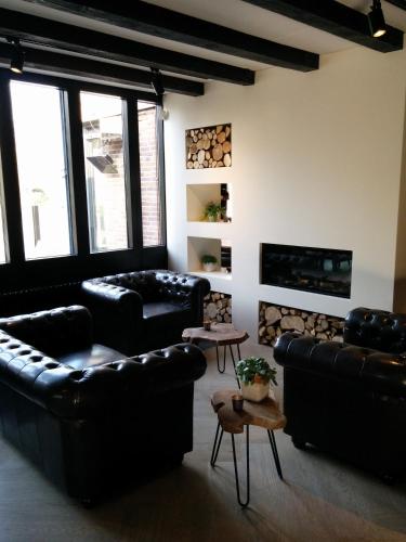 a living room with black leather couches and a fireplace at Hotel Bieze in Borger