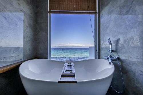 a bathroom with a tub and a window with the ocean at Burgos Reef Boutique Resort in Padre Burgos