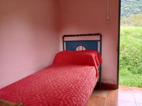 Cama en habitación con manta roja en Las Horquetas casa de campo in 