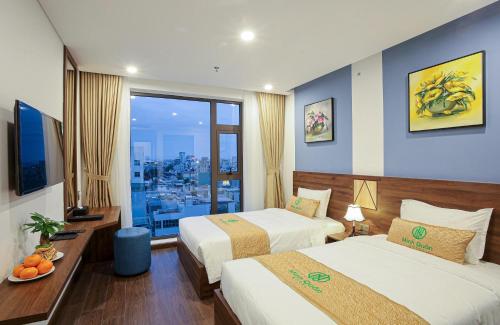 a hotel room with two beds and a large window at Minh Quan Hotel - Da Nang Center By HOS in Da Nang