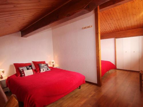 une chambre avec un lit rouge et un plafond en bois dans l'établissement Studio mezzanine pour 4 au cœur des Saisies - FR-1-594-307, à Hauteluce