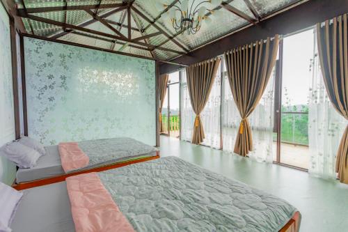 ein Schlafzimmer mit einem Bett in einem Zimmer mit Fenstern in der Unterkunft Phuong Nam Gia Trang Farmstay in Gia Nghĩa