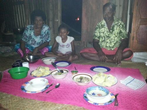 a group of people sitting on the floor with food at Yasawa Homestays in Nacula Island