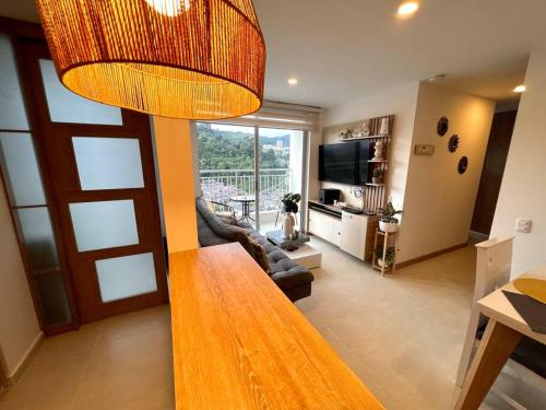 ein Wohnzimmer mit einem Tisch und ein Wohnzimmer mit einem Fernseher in der Unterkunft Espectacular vista cerca a cable plaza con Piscina in Manizales