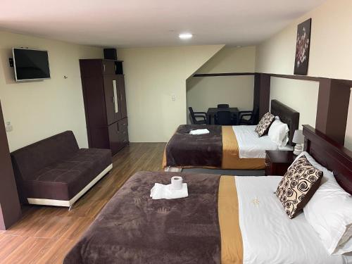 een hotelkamer met 2 bedden en een bank bij Hotel Casa Santa Lucía in Baños