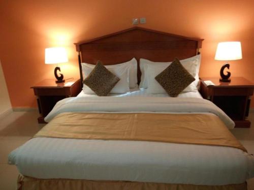 1 cama grande en una habitación de hotel con 2 lámparas en المها إن للشقق الفندقية, en Hail