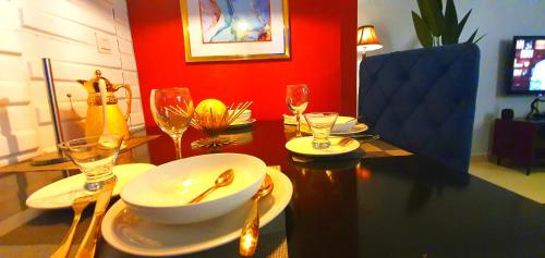 uma mesa de jantar com uma taça, pratos e copos de vinho em House of Dioma Apartments, Kubwa em Abuja