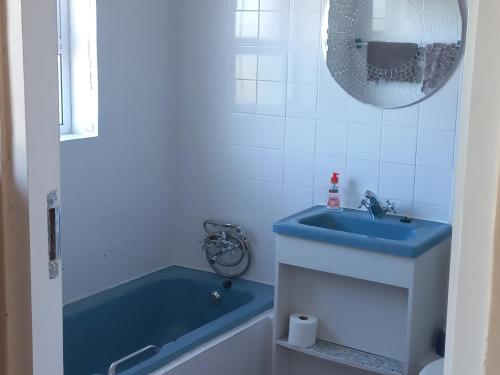 a bathroom with a blue sink and a tub at Pik 'n Wyntjie in Gansbaai