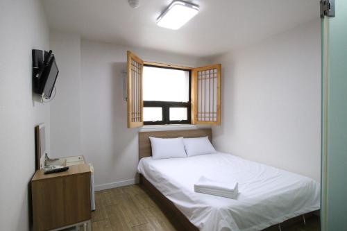 a small bedroom with a bed and a window at Stay in Blue in Seoul