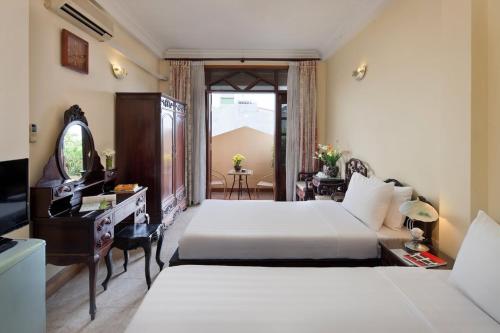 sypialnia z 2 łóżkami, biurkiem i telewizorem w obiekcie Lucky Central Hotel & Travel w mieście Hanoi