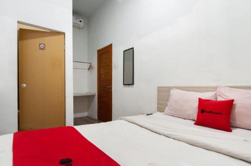 - une chambre avec un lit blanc et des oreillers rouges dans l'établissement RedDoorz At Jalan Asia Medan, à Medan