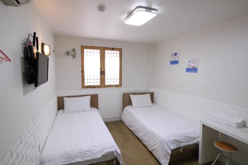 due letti in una stanza con pareti bianche e una finestra di Stay in Blue a Seul