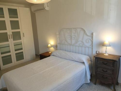 a bedroom with a white bed and two night stands at Fantástico duplex en el centro de Osuna in Osuna