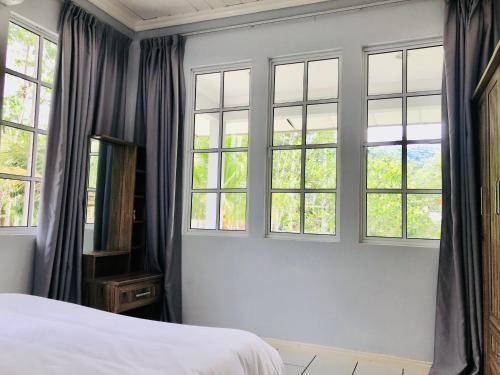 a bedroom with four windows and a white bed at Grace Guesthouse in Kota Belud