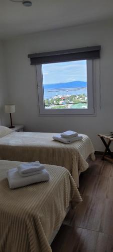 two beds in a room with a large window at Lalúan departamento temporario in Ushuaia