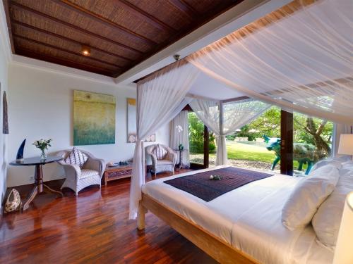 a bedroom with a large bed and a desk at Sungai Tinggi Beach Villa by Elite Havens in Canggu