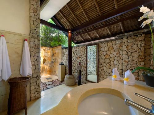 baño con lavabo y pared de piedra en Sungai Tinggi Beach Villa by Elite Havens, en Canggu