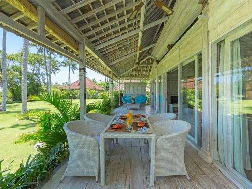 eine Veranda mit einem Tisch und Stühlen darauf in der Unterkunft Sungai Tinggi Beach Villa by Elite Havens in Canggu