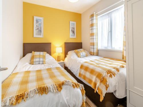 two beds in a room with yellow walls at Uk43576 - Bramble Cottage in Begelly