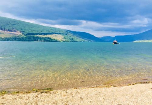 a large body of water with a boat in the distance at Seal Cove Cabin - Luxury Glamping in Cairndow
