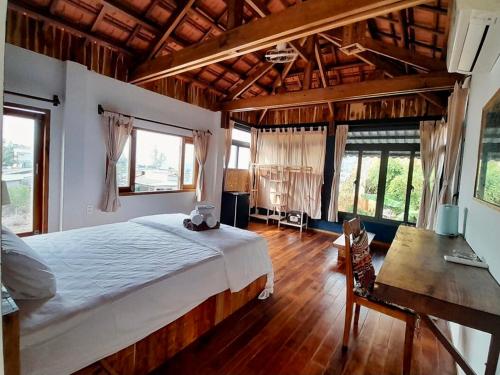a bedroom with a bed and a desk and windows at Eco Lagoon in Phu Quoc