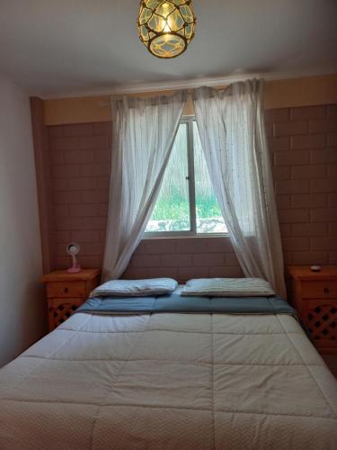 a bedroom with a bed with a window and a chandelier at El pimiento Horcon valle elqui, 4 personas in La Serena