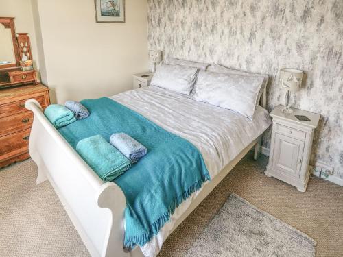 a bed with a blue blanket and pillows on it at Strawberry Cottage in Haworth
