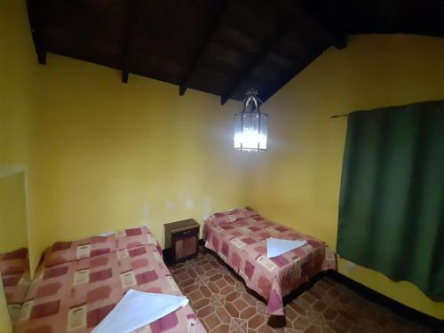 Habitación con 2 camas y lámpara de araña. en Hotel Posada San Felipe, en Antigua Guatemala