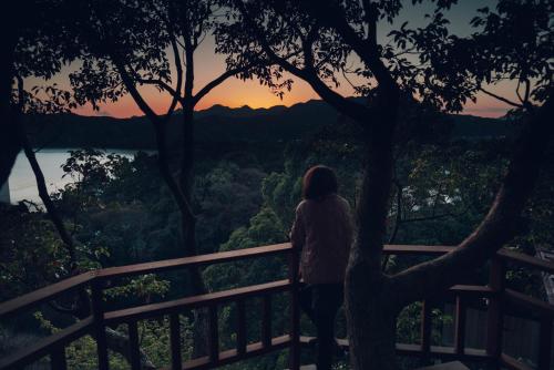 Una donna in piedi su una recinzione che guarda il tramonto di Villa Yumigahama a Minamiizu