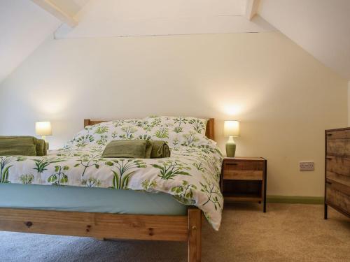a bedroom with a bed and two lamps and a dresser at Drapers Cottage in Foxton