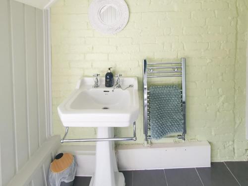 Drapers Cottage في Foxton: حمام مع حوض أبيض وجدار من الطوب الأبيض