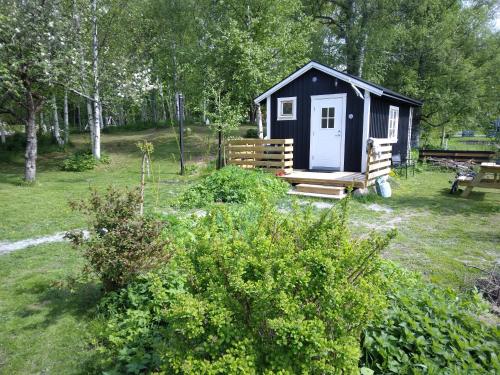 a black cabin with a white door in a yard at Countrycabin Bergslagen stuga in Ramsberg