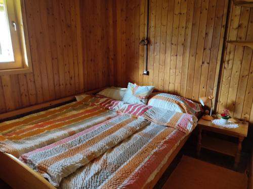 a bed in a room with a wooden wall at Beehive cabin on a farm in Radovljica