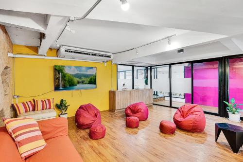 a living room with red chairs and a yellow wall at Chill Inn Bangkok in Bang Kapi