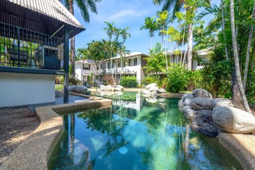a swimming pool in front of a house with palm trees at Seascape Holidays at Reef Terraces on St Crispins in Port Douglas