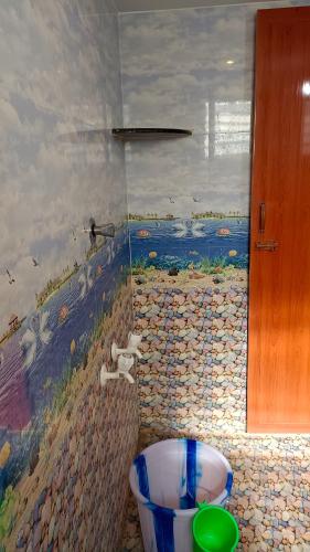a bathroom with a painting on the wall and a tub at Sathya Guest House in Tiruvannāmalai
